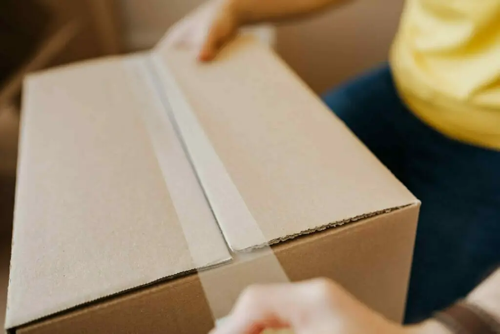 A woman is opening up a cardboard box.