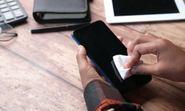 A person wiping a smartphone with a cloth