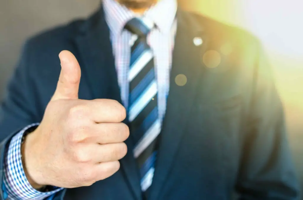 A man in a suit is giving a thumbs up