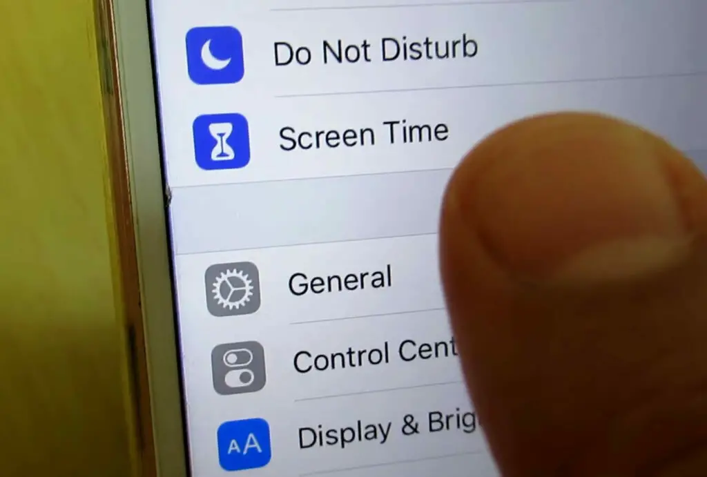 A person is pointing at the screen time on an iphone