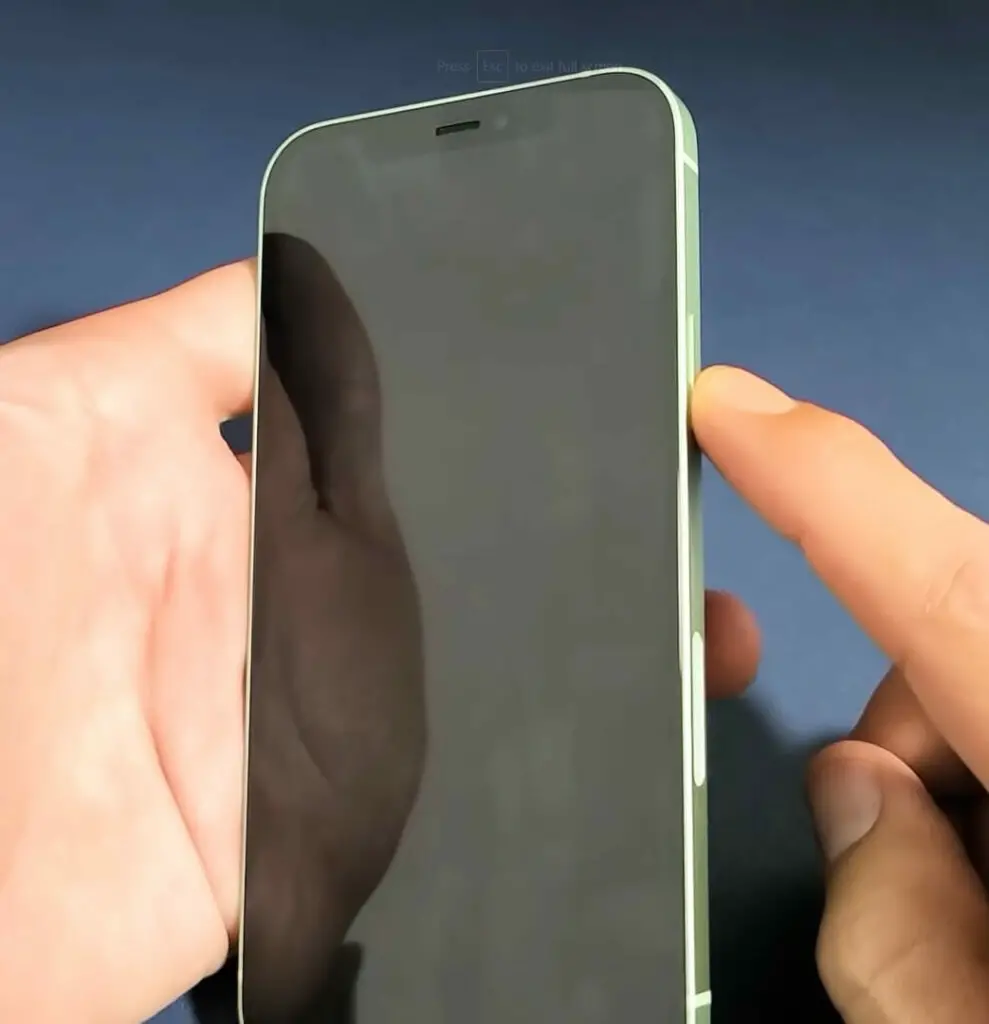 A person's hand is holding an iPhone while pressing the turn off button