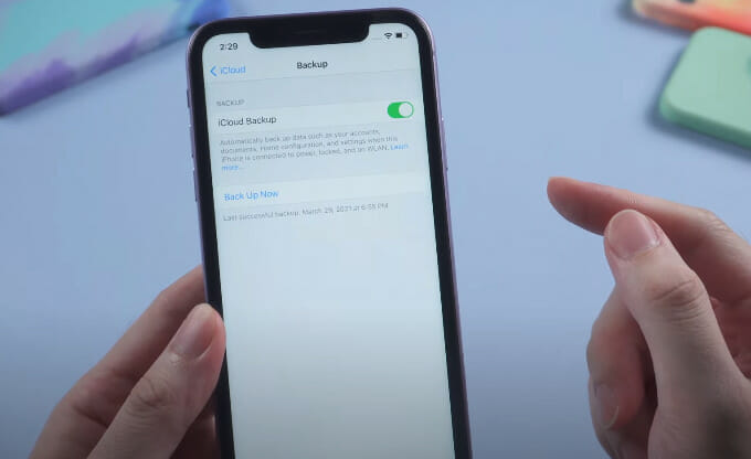 A person is holding a iPhone enabling the iCloud back up
