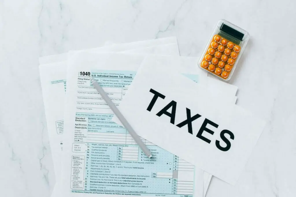 A stack of tax forms and a calculator on a marble table