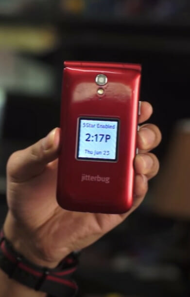 A person is holding up a red jitterbug phone