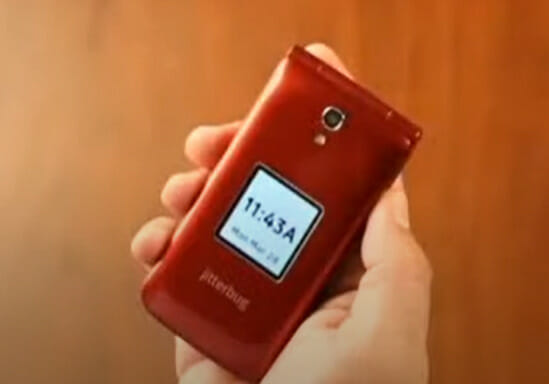 A person holding a red jitterbug phone with a time display in it