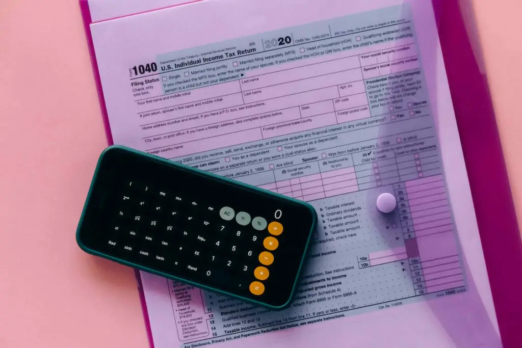 A calculator on the phone sits on top of a tax form document