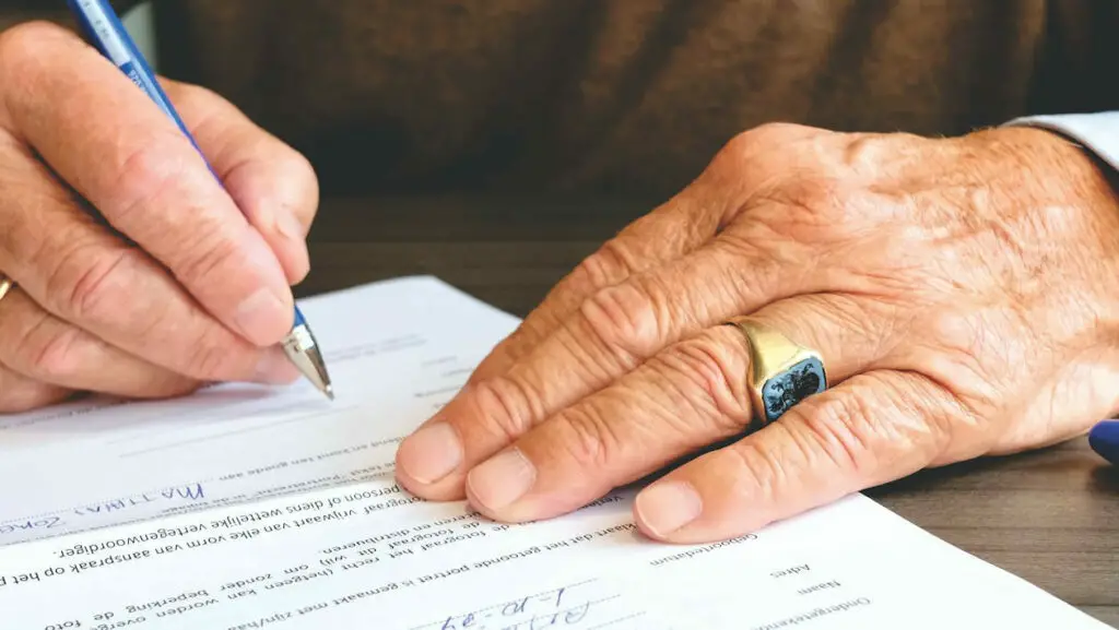 An older man signing a document with a pen