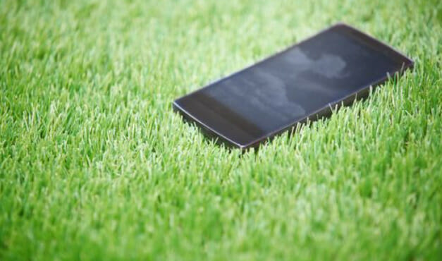 A smartphone is sitting on top of a green grass