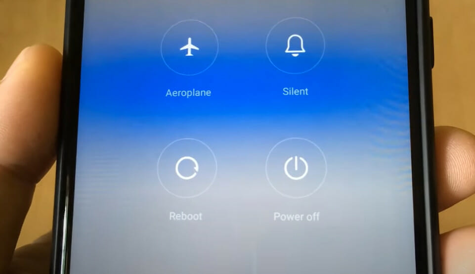 A person holding a phone showing the Aeroplane, Silent, Reboot and Power off options