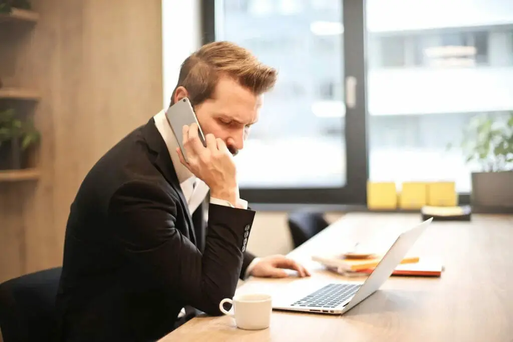 A business man in suit working on his desk while on the phone
