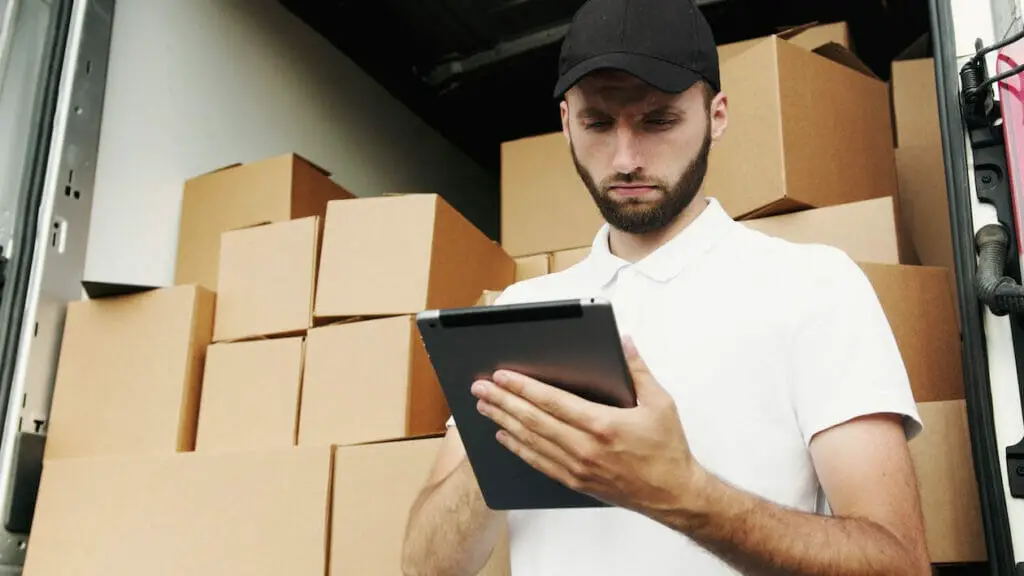 A delivery man with the packages on a trailer at the back