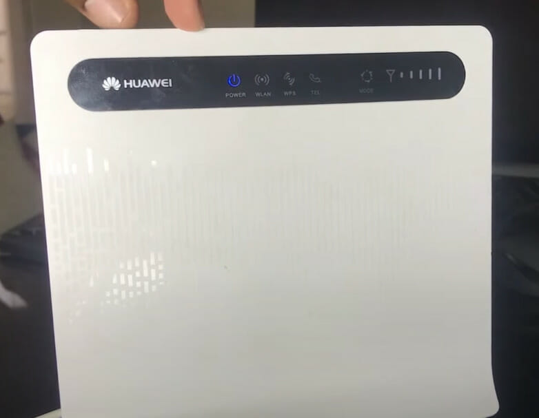 A person is holding up a HUAWEI router
