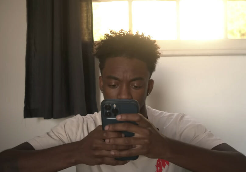A man looking at his phone while sitting in bed