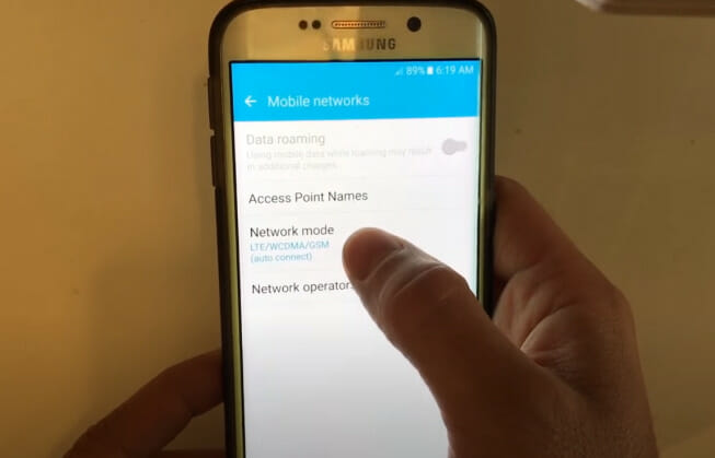 A person holding a Samsung phone tapping on the Network mode setting