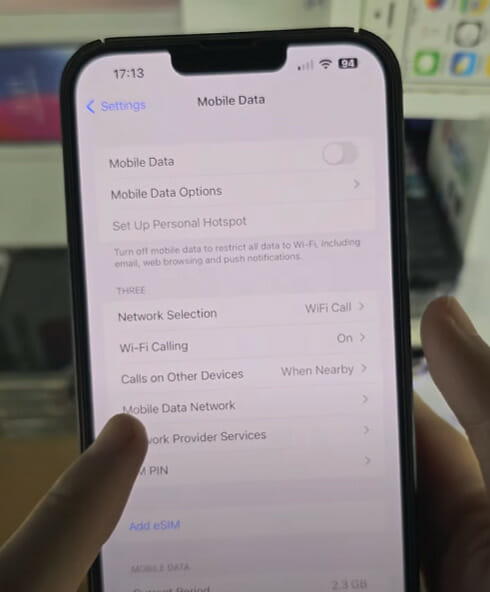 A person is holding up an iPhone tapping the Mobile Data Network option on the setting