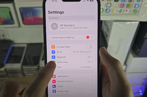 A person is holding up an iPhone in a store and tapping Mobile Data on the Settings