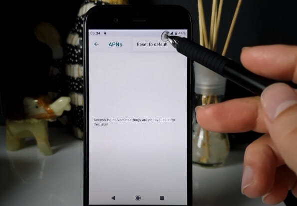 A person is using a digital pen to reset APN settings on the phone