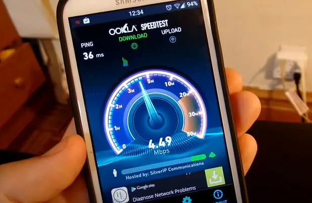 A person is holding up a cell phone with OOKLA internet speedtest on it
