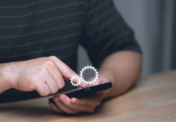 A man using a smartphone with gears icon in it