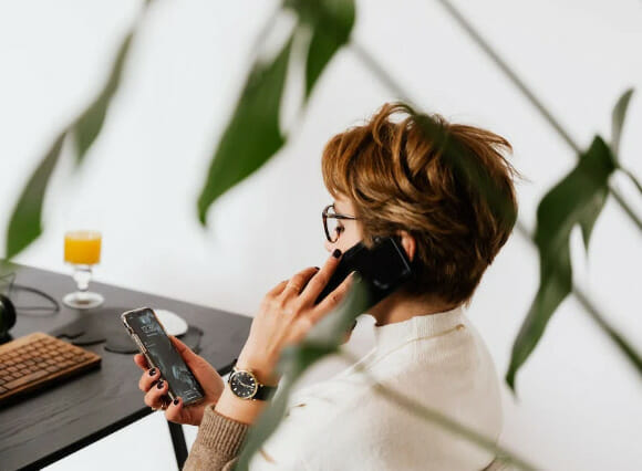 A woman talking on a cell phone while sitting at a desk.