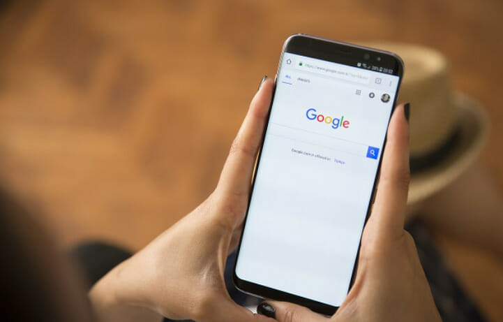 A woman holding a phone with google search displayed on it