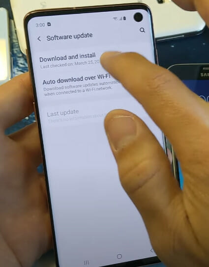 A person tapping on the 'Download & Install' option for a phone's software update