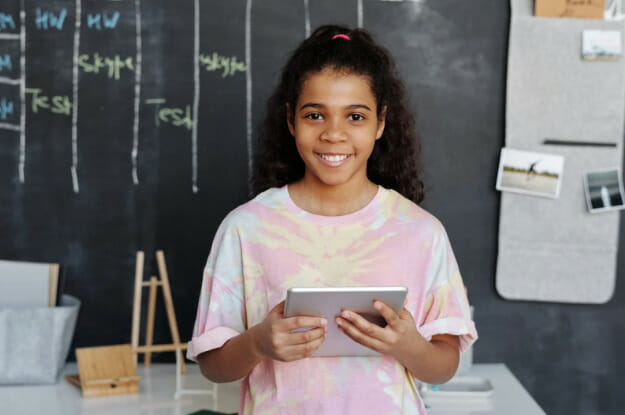 A girl holding a tablet in front of a chalkboard