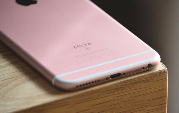 A pink iphone sits on top of a wooden table
