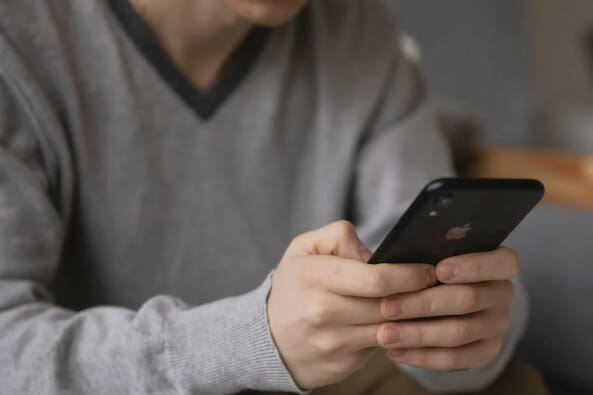 A man sitting on a couch holding an iPhone