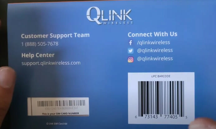A person is holding up a QLINK wireless sim card