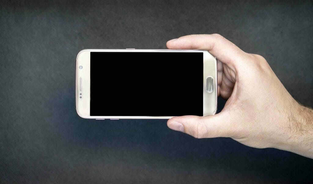 A hand holding a smartphone with a blank screen.