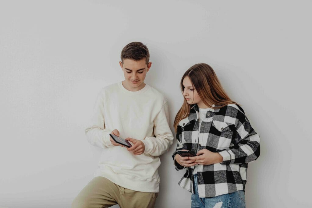 A man and a woman holding their phones with the man showing something on his phone to the woman