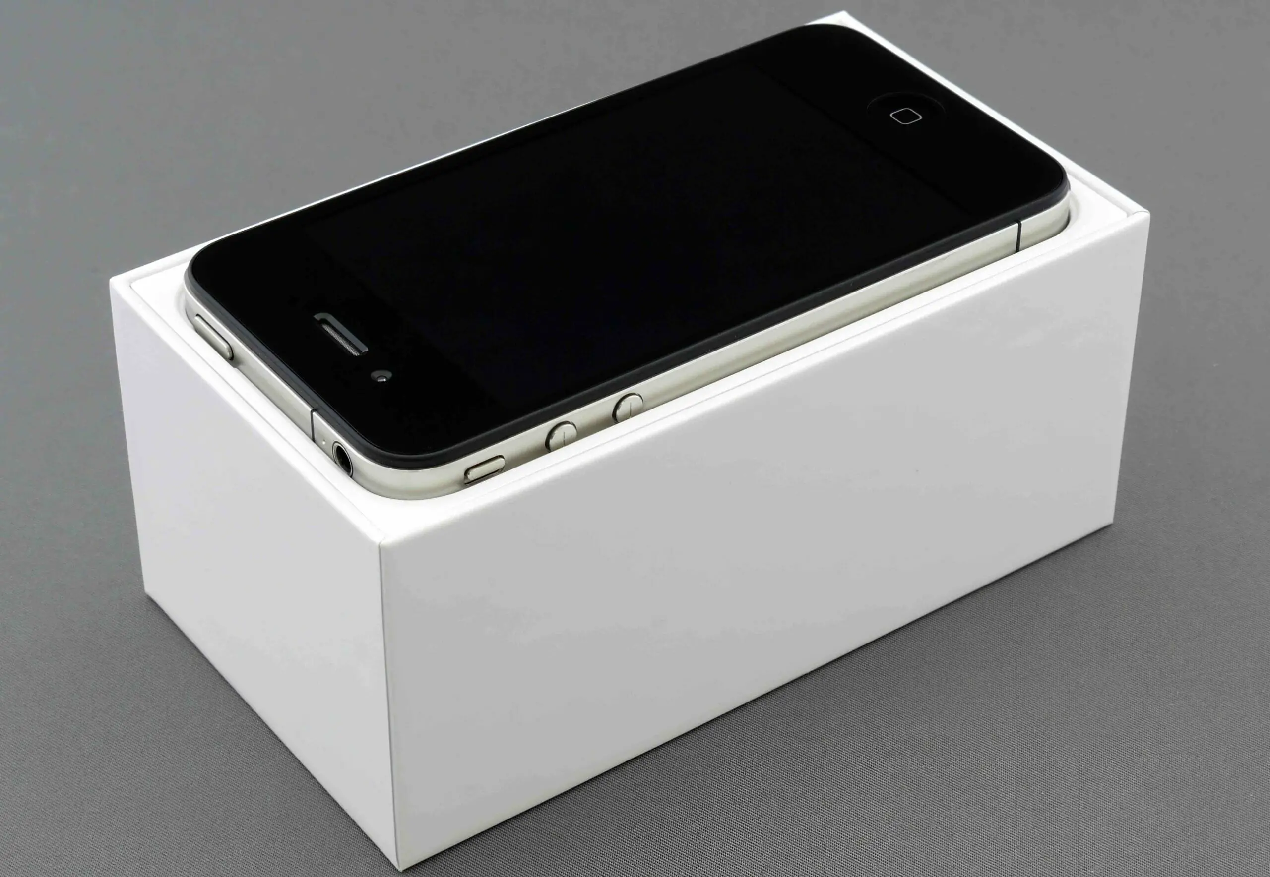 A phone at the top of its white box in a grey table