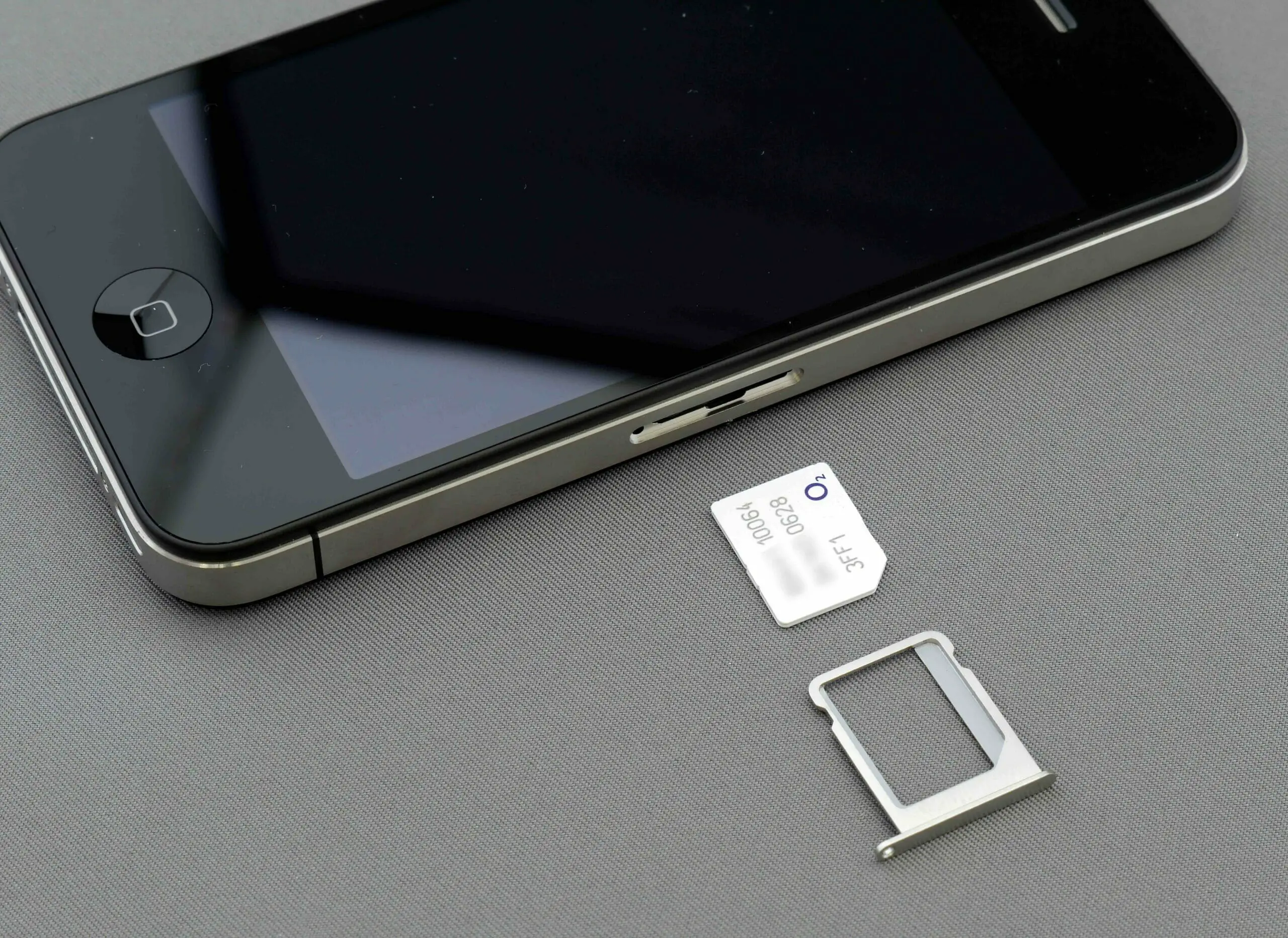 A phone, sim card and its sim card holder on the table