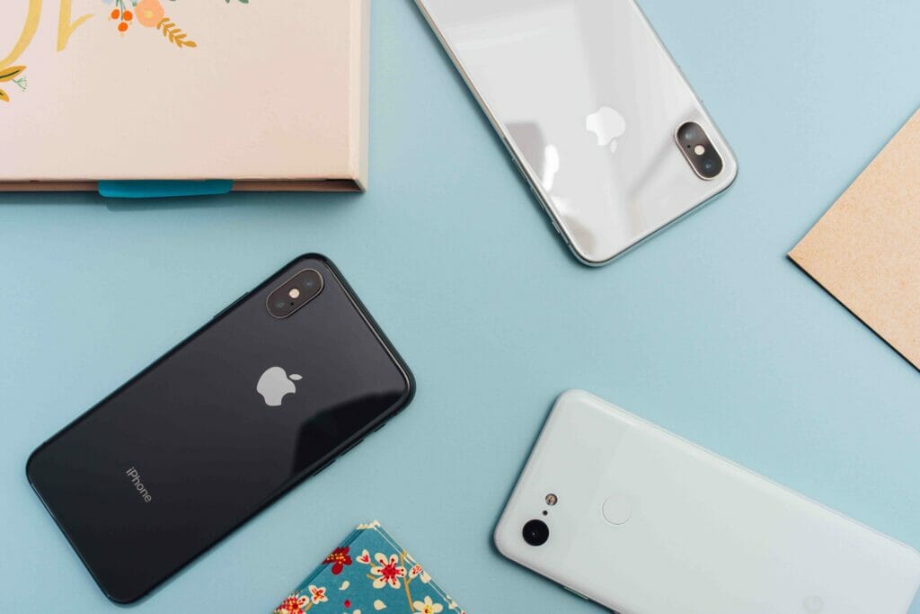 A top shot of three phones on a blue background along with notebooks and paper