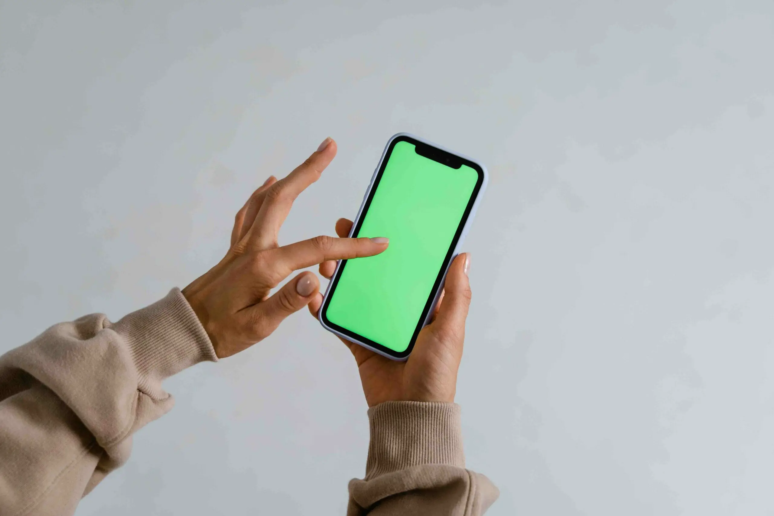 A woman holding a phone showing the green screen in it