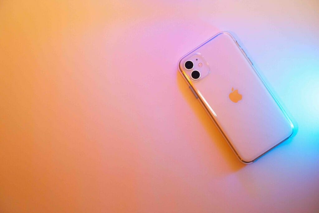 An iphone in a pastel shade table with blue lights reflection