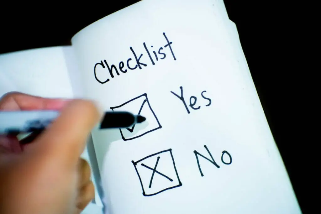 A person writing on the Checklist note with Yes and No option