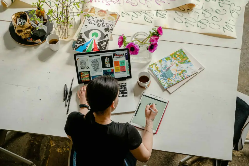 A woman working at a desk with a laptop and pens