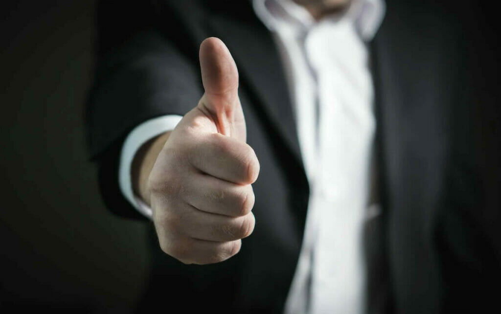 A man in a suit is giving a thumbs up