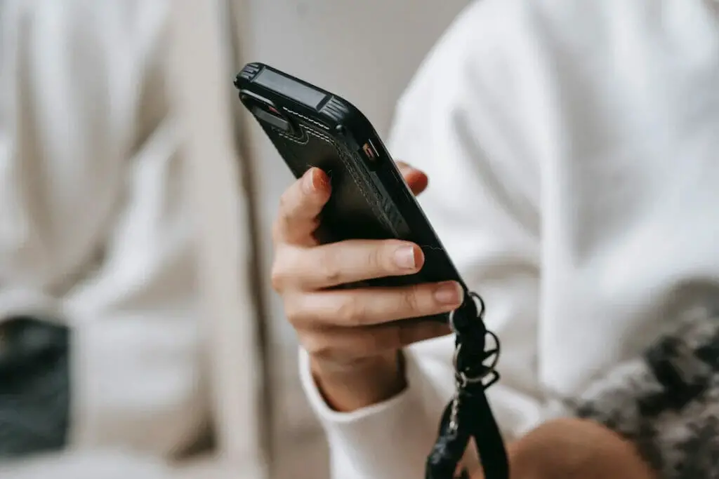 A woman holding a phone with black leather cover in it