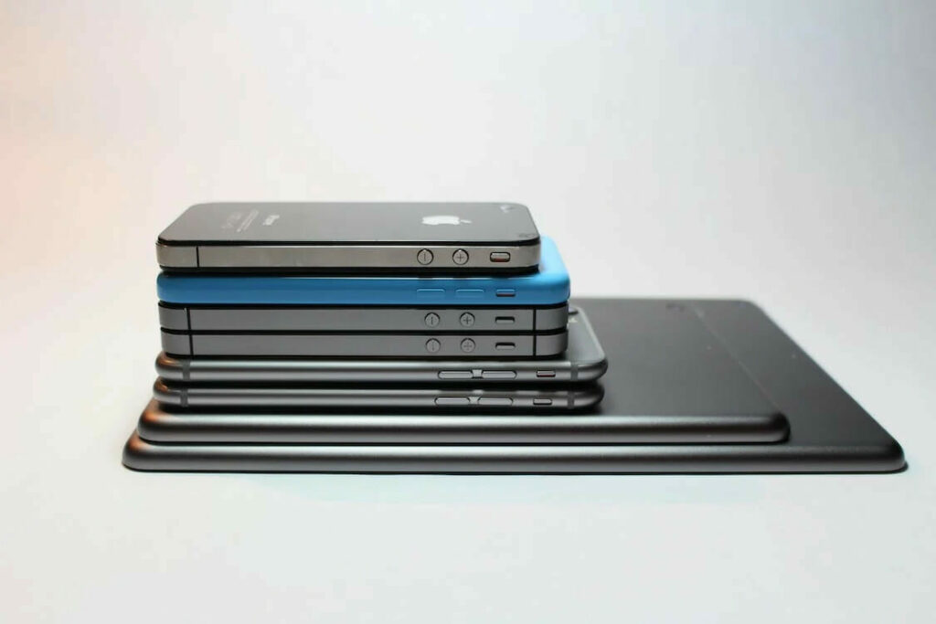 A stack of iphones, ipad and laptop stacked on top of each other