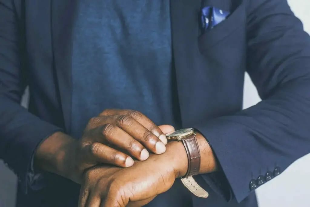 A man in a suit is adjusting his watch