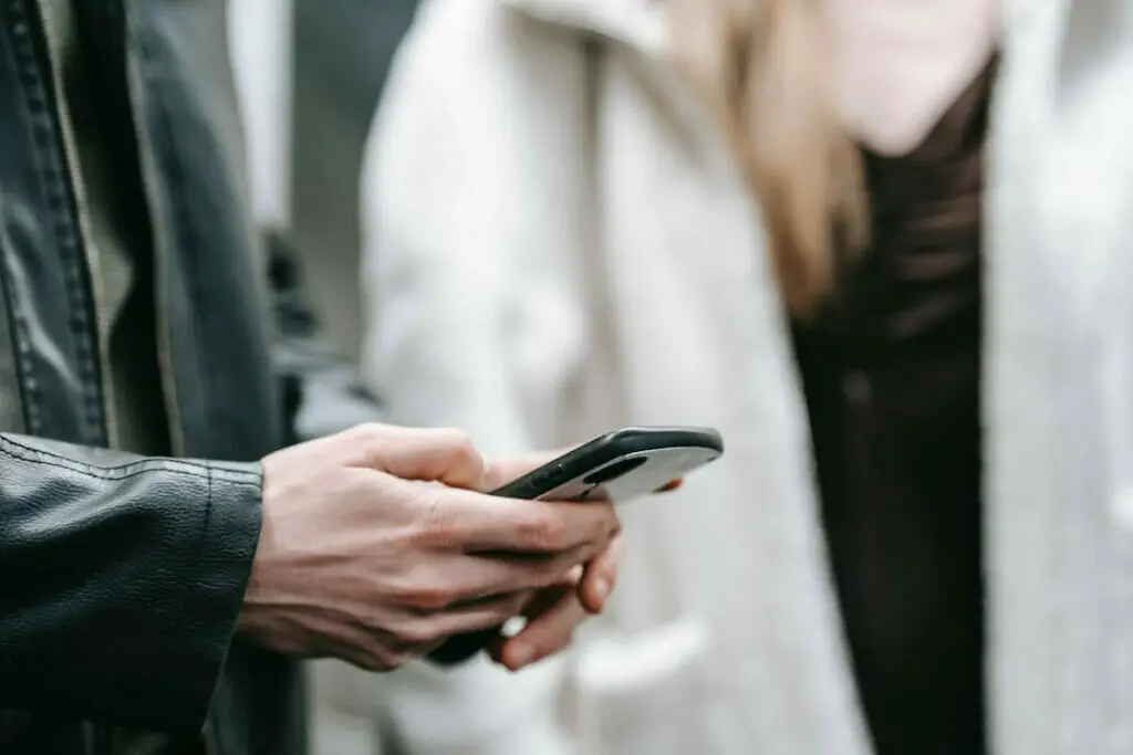 A man is holding a cell phone while a woman is standing next to him