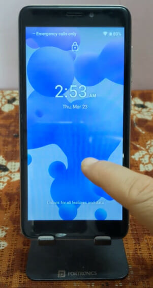 A person holding an LG Android phone with blue bubble like screen saver on it