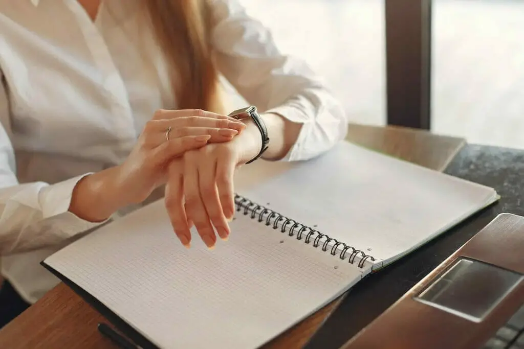 A woman is sitting at a desk with her hands on a notebook