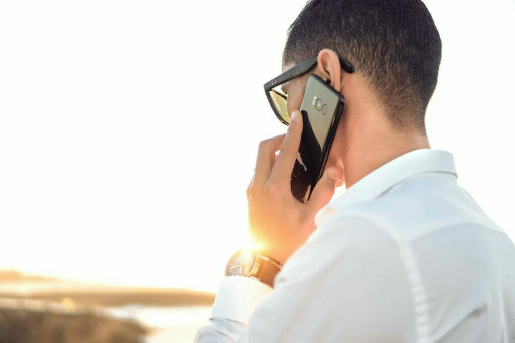 A man in a white shirt is talking on his cell phone