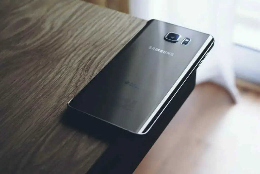 Black Samsung phone on a wood table