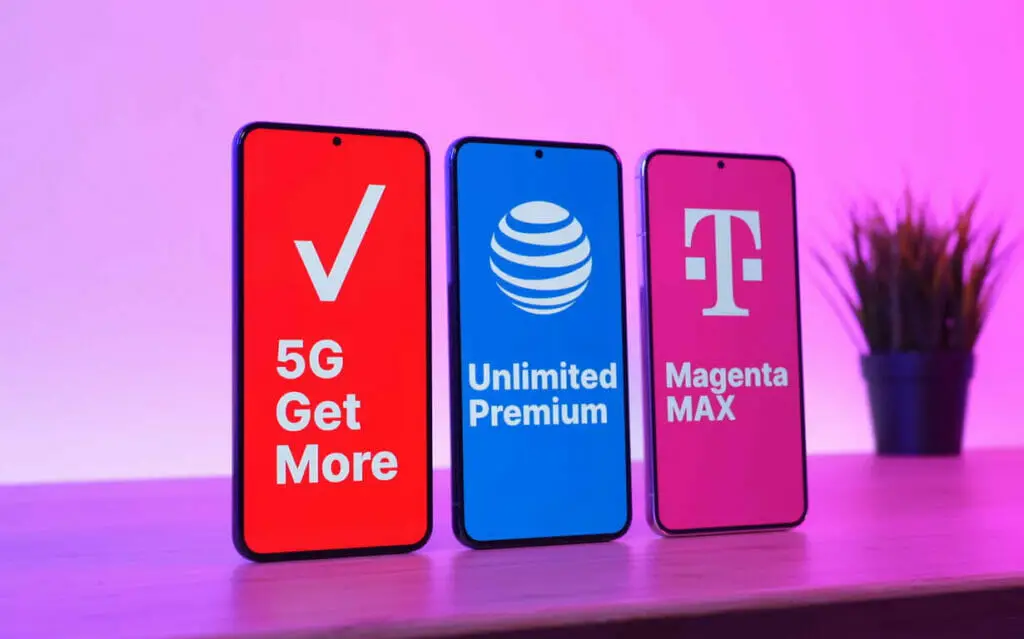 Three cellphone on a table and with pink background in a different logo such Verizon, AT&T and T-Mobile