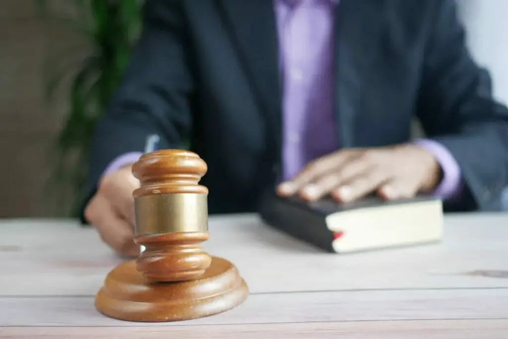 A man holding a bible on his left hand and a gavel on the right hand